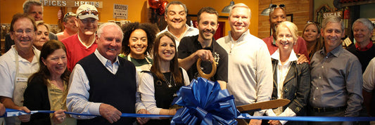 Franchise owners cutting blue ribbon at grand opening ceremony