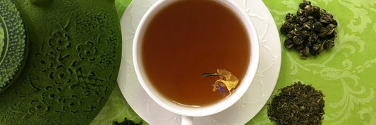 Green tea in white mug with loose leaf tea next to it