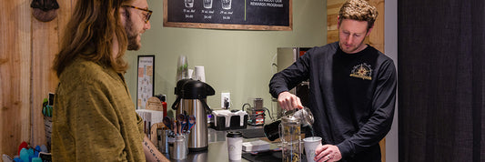 Man at tea bar while tea barista makes and pours him tea.