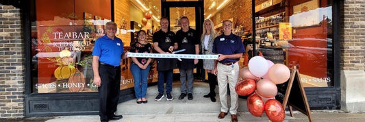 Franchise owners holding a ribbon in front of store to cut during opening ceremony