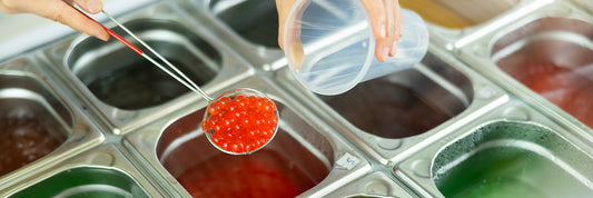 Bright colored bobas at a bubble tea shop being scooped out.