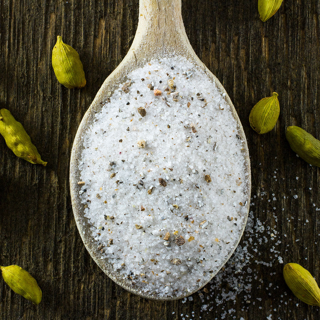 Cardamom Sugar in spoon surrounded by cardamom green seeds