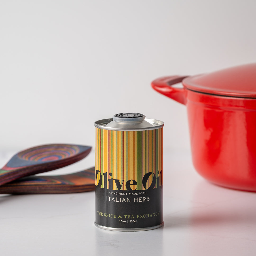 Italian Herb Olive Oil next to red pot and rainbow pakkawood spoons