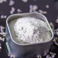 Lavender Lemon Sugar in square tin surrounded by dried lavender buds