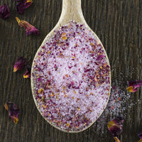 Rose Sugar in wood spoon surrounded by rose petals